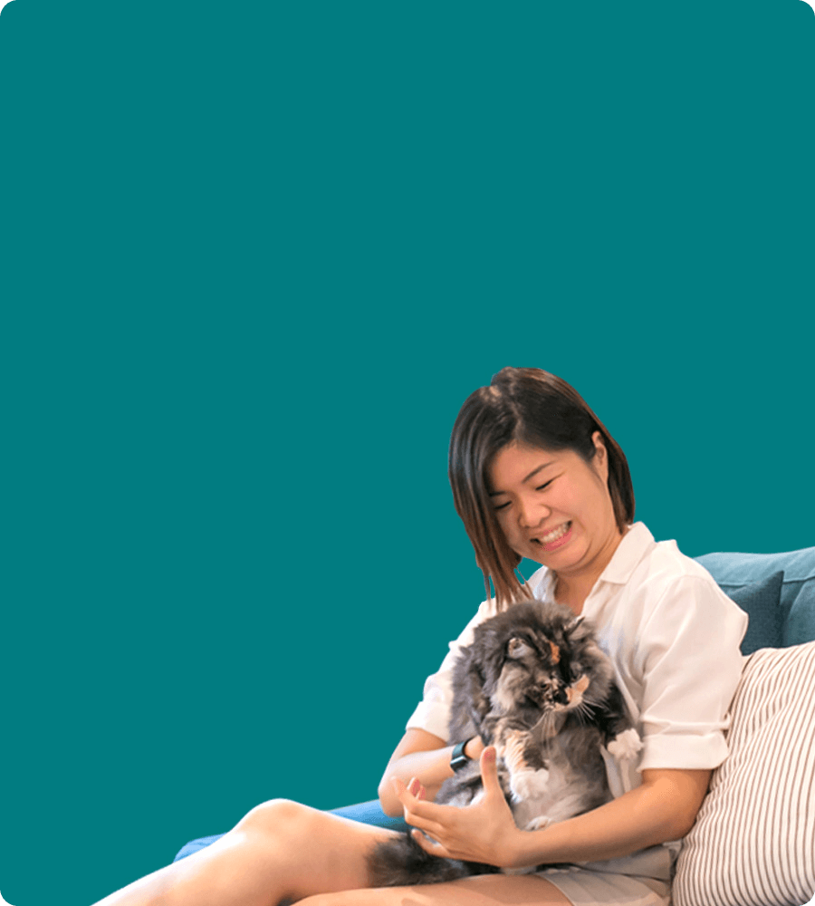 woman holding a cat in a sofa with teal wall